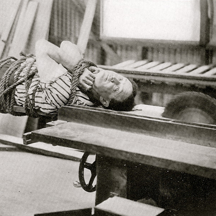 Image of a tied up Harry Houdini on a running table saw. Buzz. Buzz.